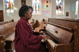 Pianiste gospel en robe de chœur jouant un hymne émouvant sur un piano d'église